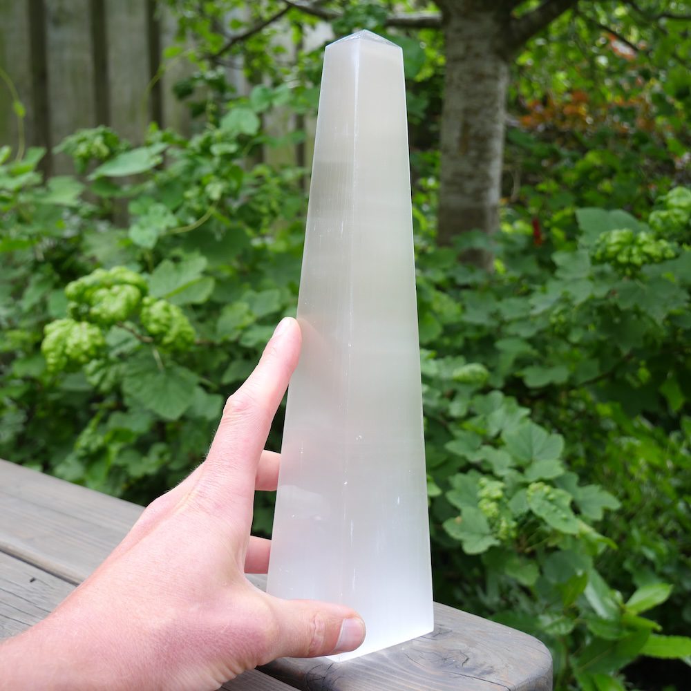 Fraaie seleniet obelisk XL van maar liefst 30cm hoog - zijaanzicht met hand
